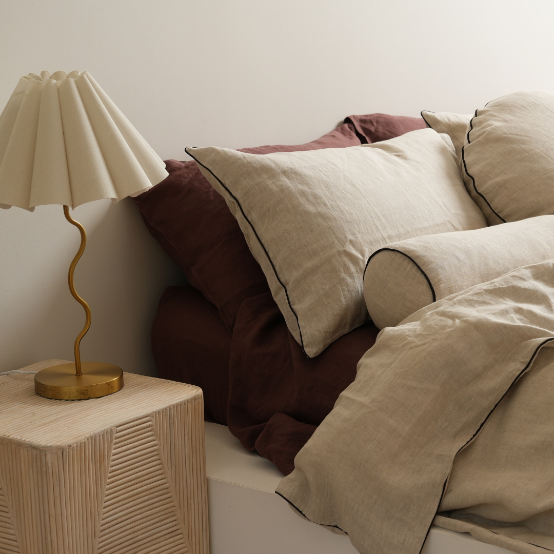 100% french flax linen piped feather filled bolster cushion in natural oat/ black, close-up